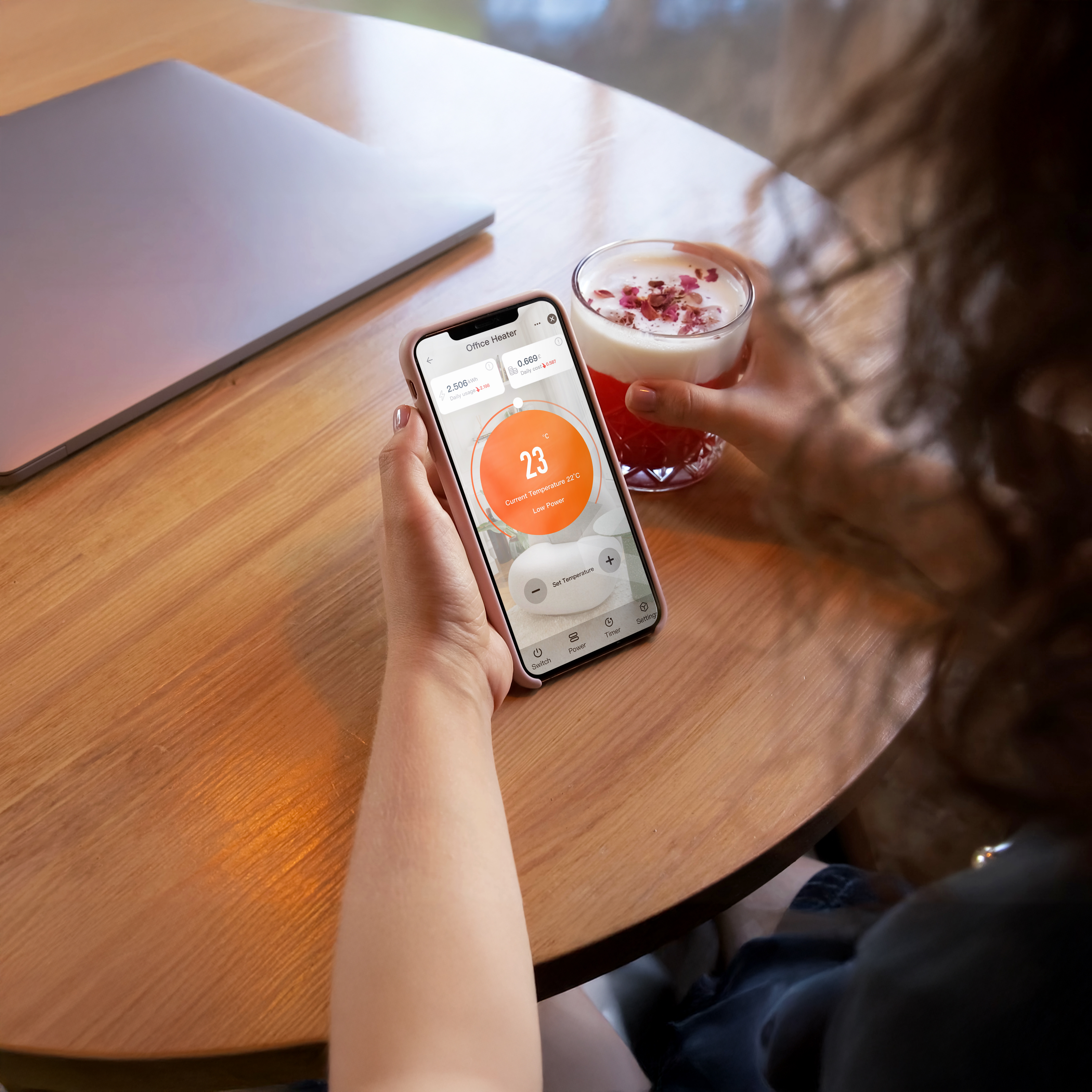 a person holding a phone and a drink on a table